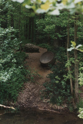 Photograph of sculpture Cone and Vessel with stream in foreground